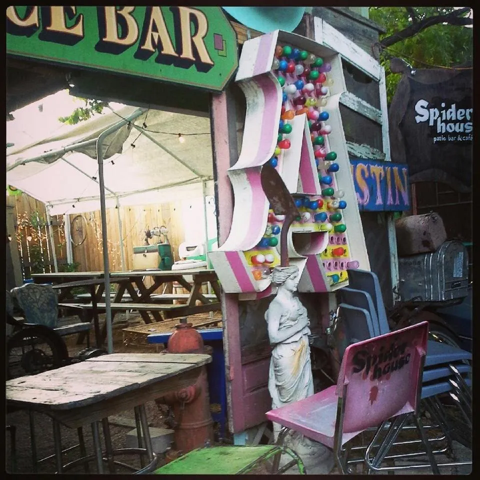 The Spider House patio: mismatched tables, a plaster statue and a giant letter A studded with bulbs